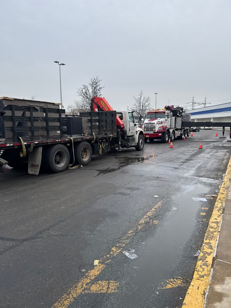 Crane and flatbed trucks on a commercial rooftop job