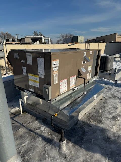 Heat pump equipment running on a snowy Staten Island roof